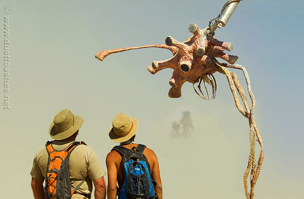 Two men looking at virus like art sculpture during Burning Man dust Storm