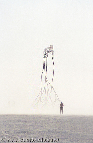 Woman standing in front of  giant art installation made of rods and wires
